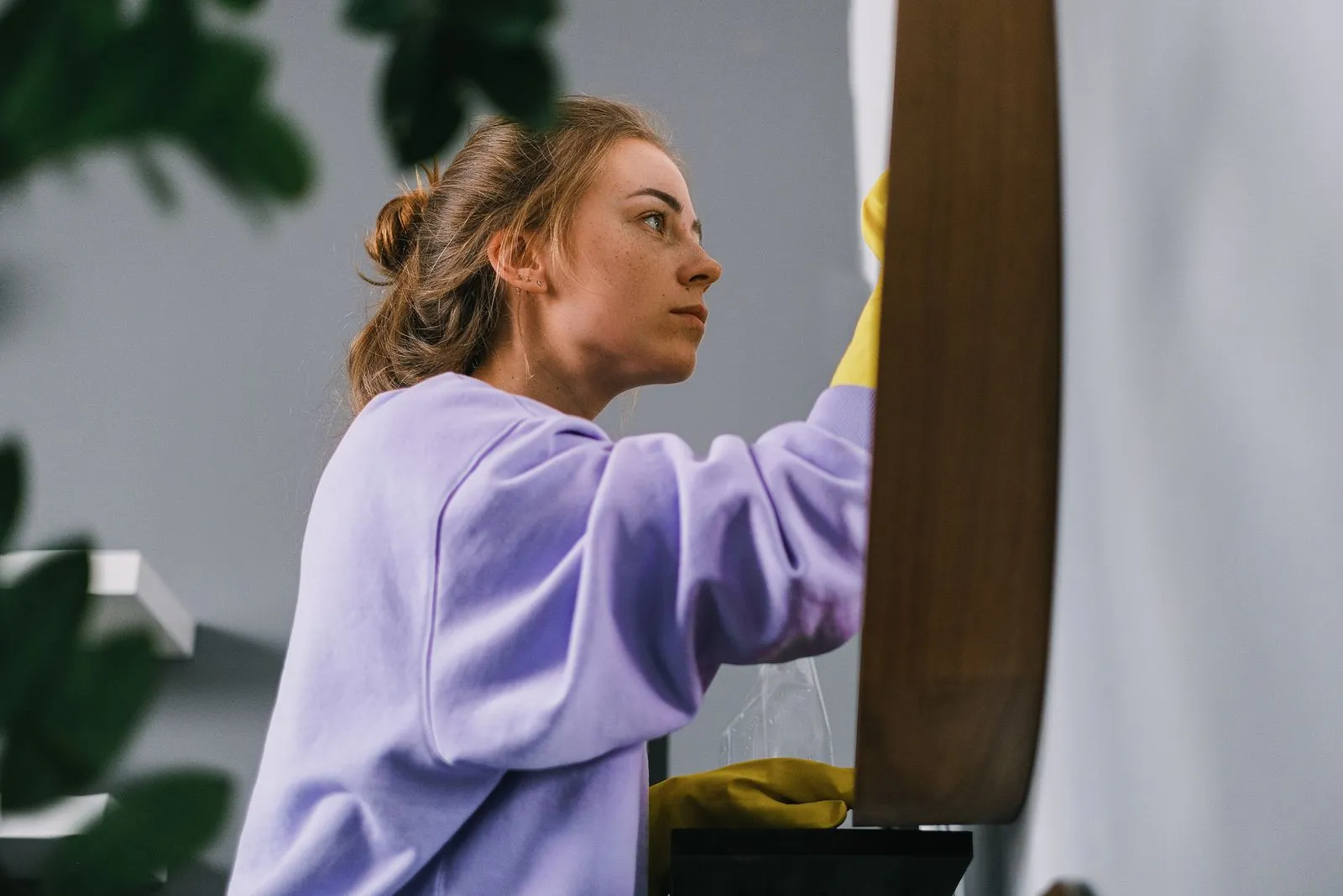 Cleaner wiping a mirror in a home